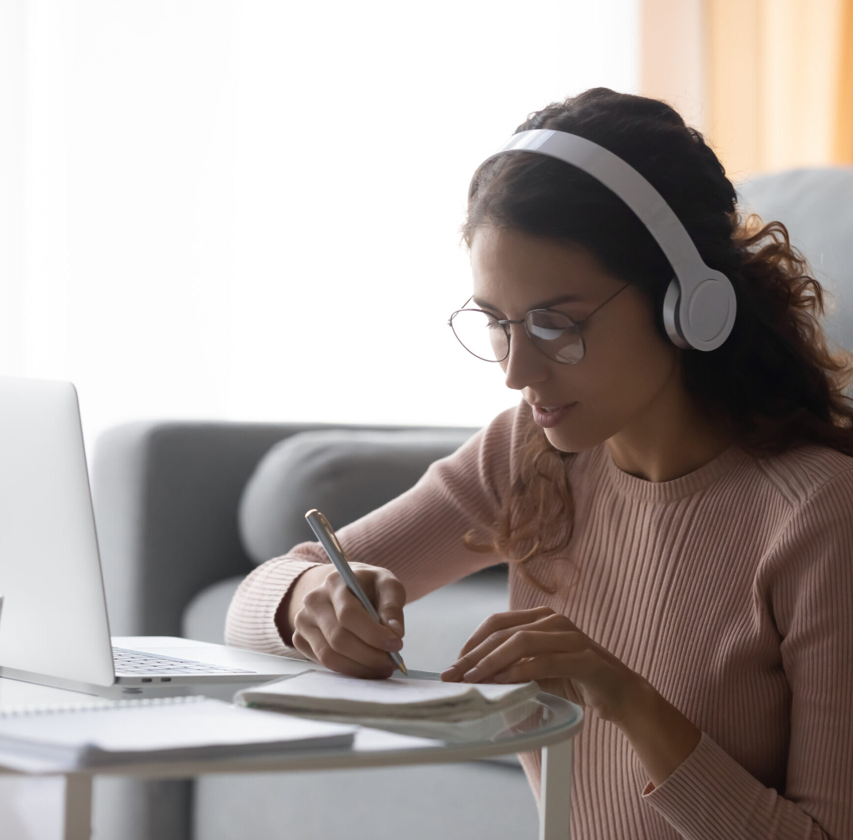 Focused,Woman,Wearing,Headphones,Writing,Notes,,Sitting,On,Floor,At